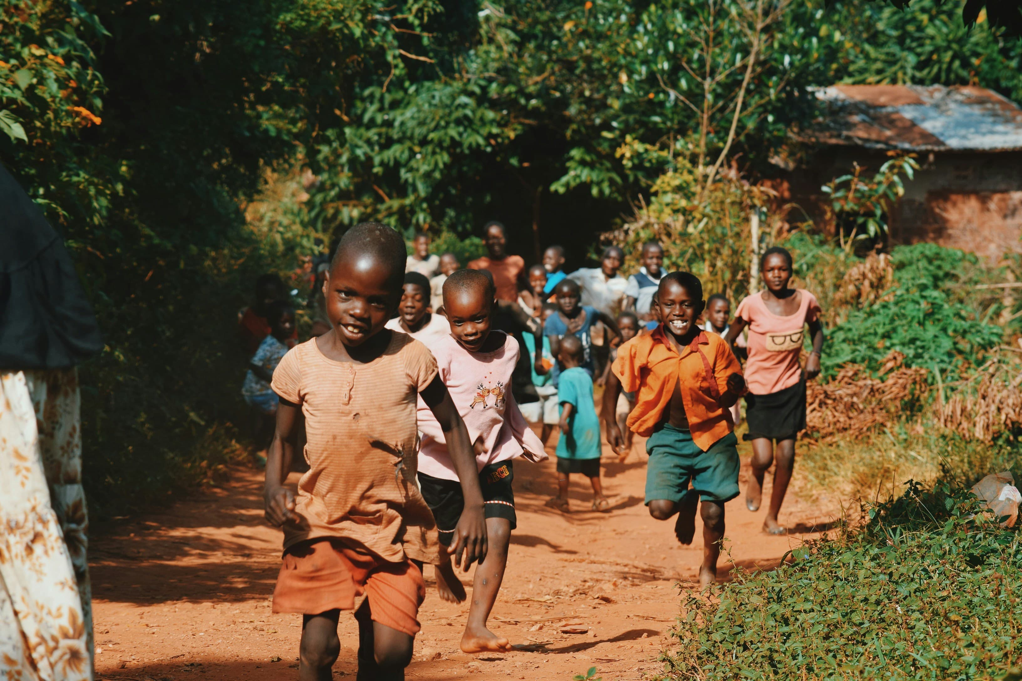 A group of smiling children running towards the camera.