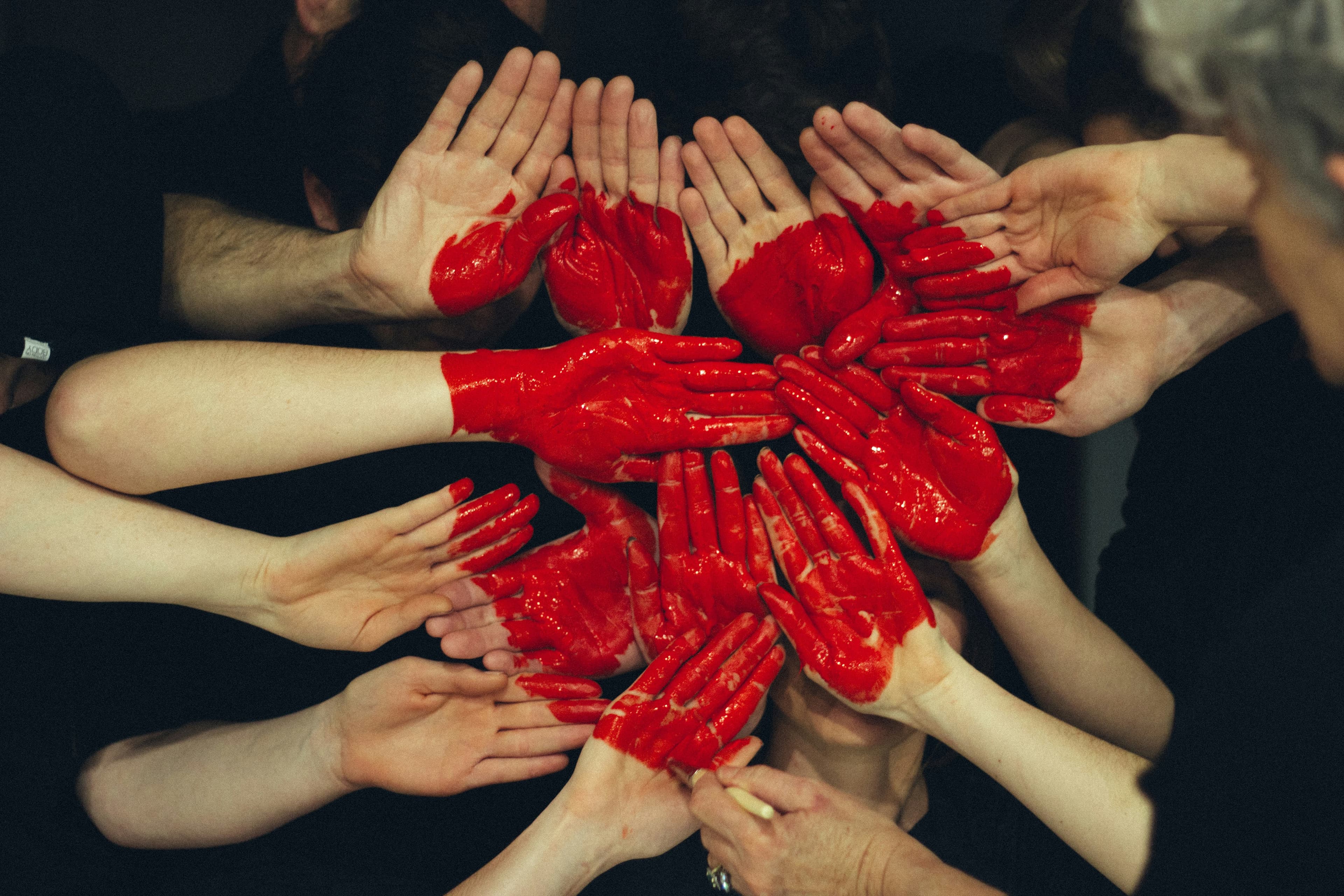 Hands painted with red paint forming a heart shape.