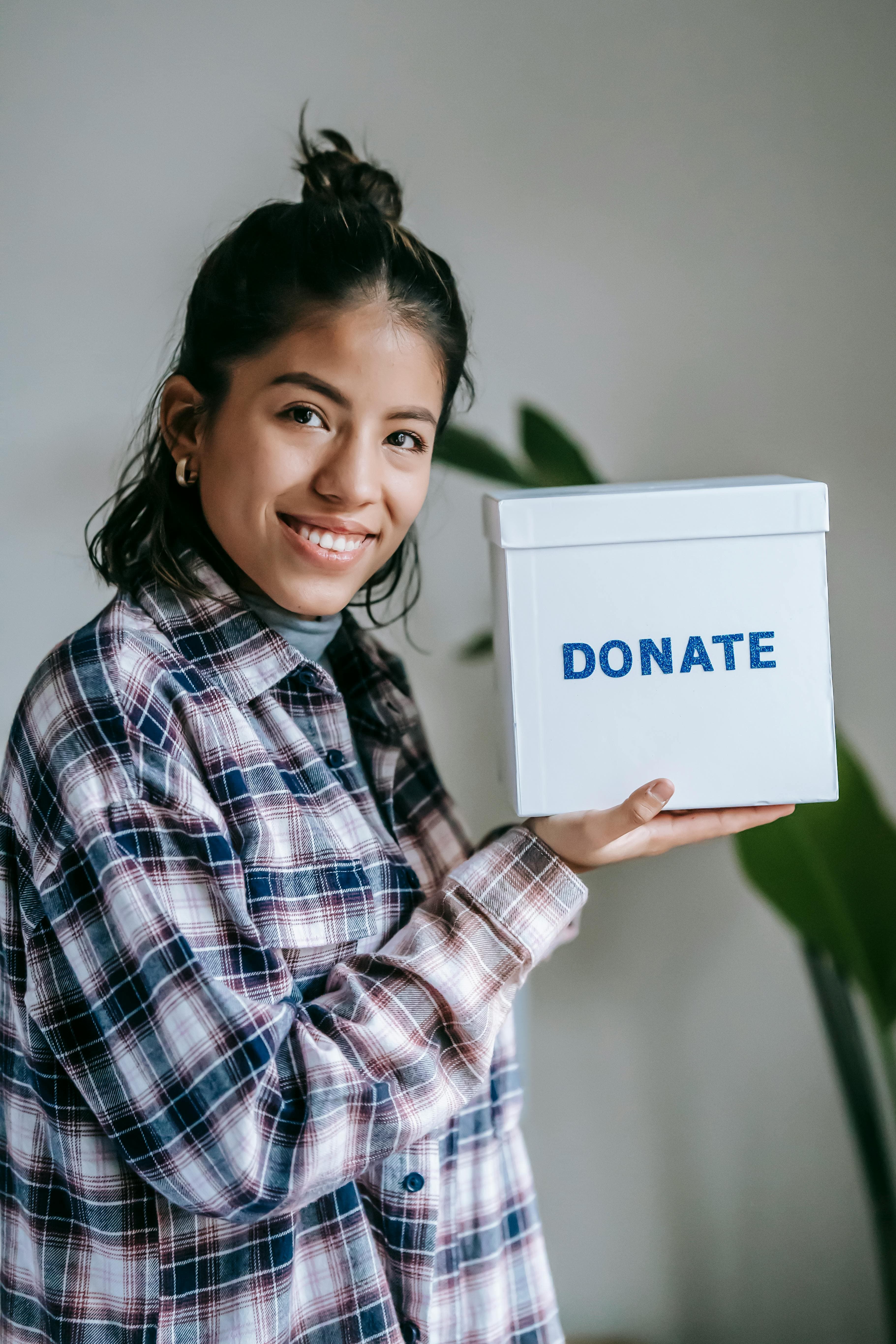 Smiling woman holding a box with 'Donate' text on it.