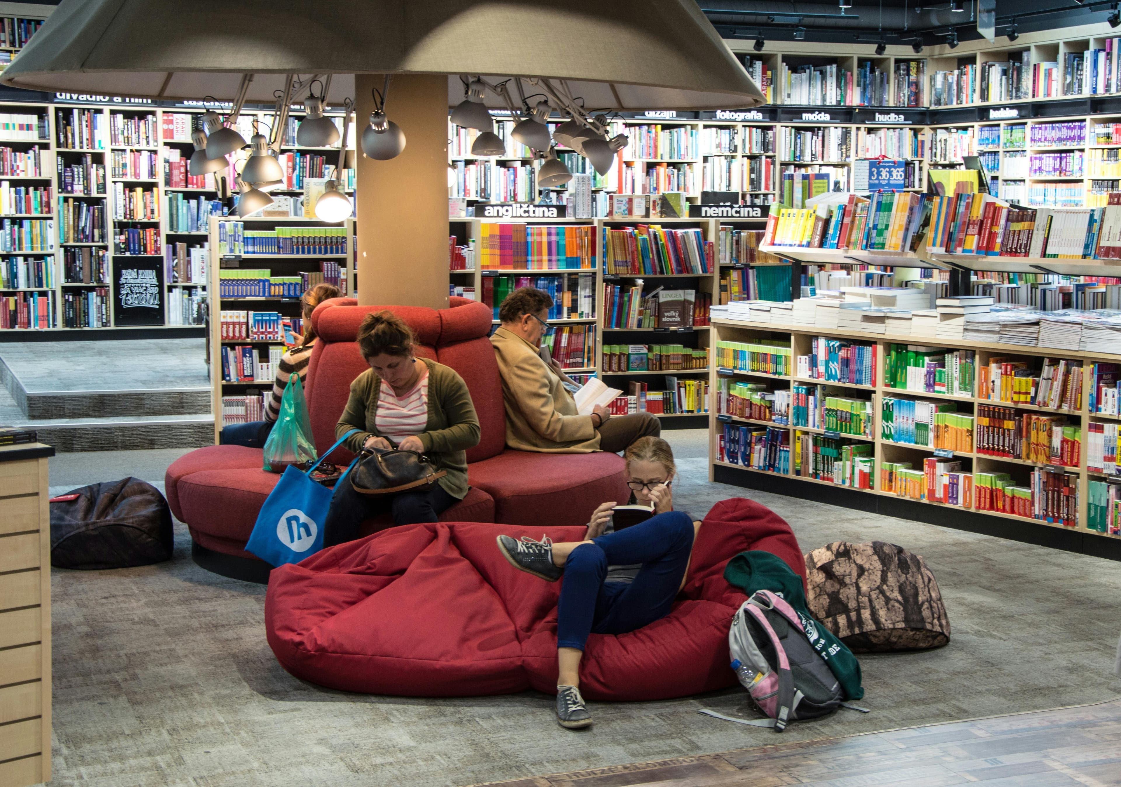 A cozy bookstore seating area with bean bags, a large lamp, and shelves lined with colorful books, creating a relaxed reading environment.