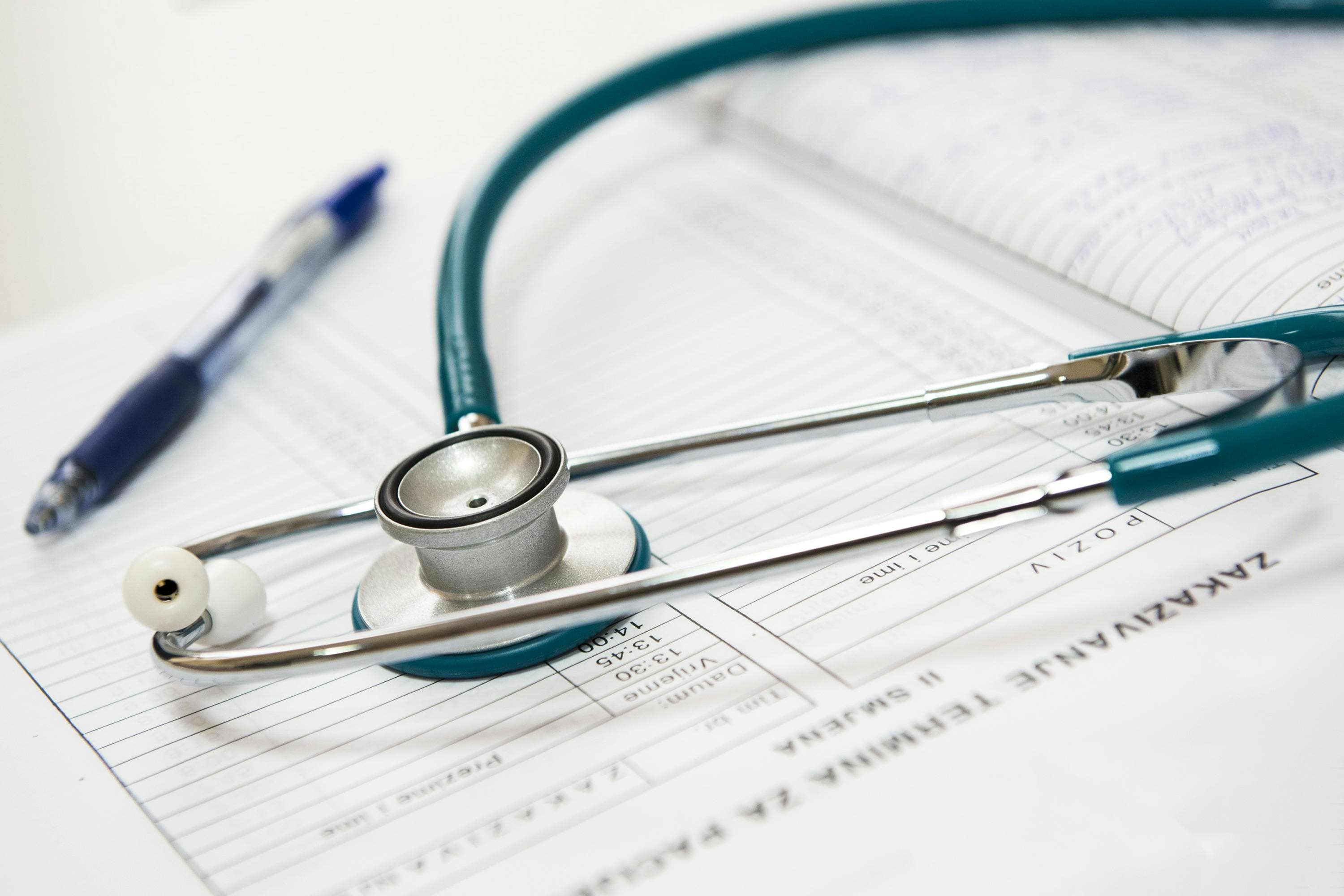 A stethoscope rests on top of a medical chart with a pen nearby, symbolizing healthcare and patient documentation.